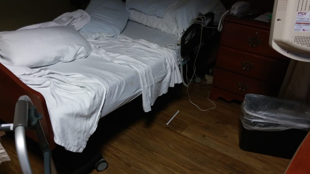 A dimly lit bedroom with an unmade bed and scattered items on the floor.