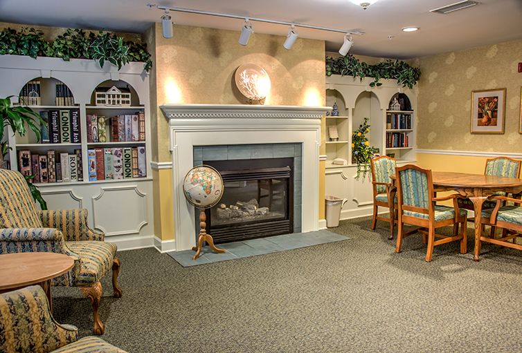 Cozy library interior with a fireplace, bookshelves, globe, and seating area.