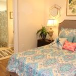A cozy bedroom with colorful bedding, a bedside lamp, and a plant for decoration.