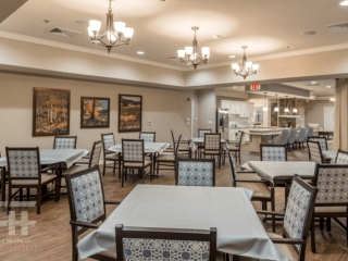 An elegant dining room with multiple tables and chairs, adorned with chandeliers and wall art.
