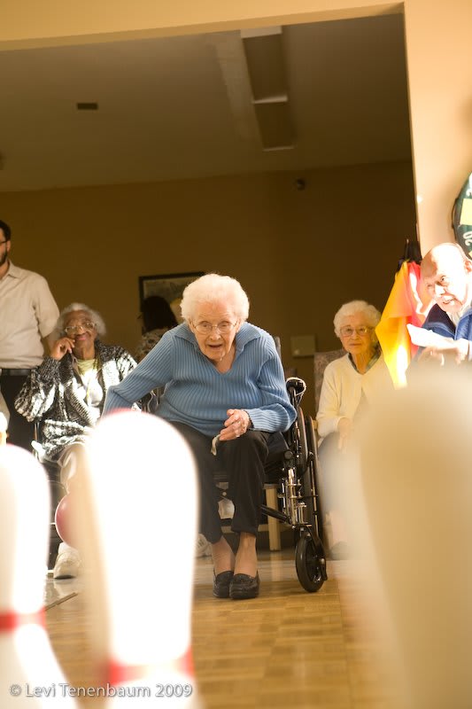 Elderly individuals participating in a fun bowling activity at a nursing home.