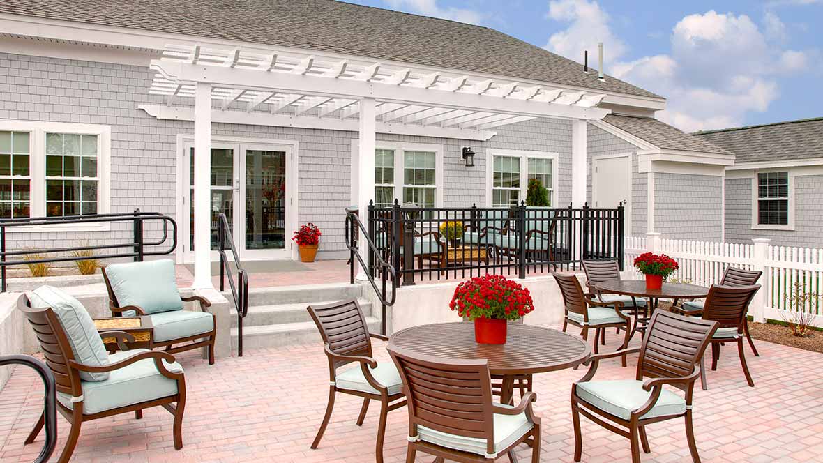 A well-furnished patio with a pergola, featuring outdoor seating and flower arrangements.