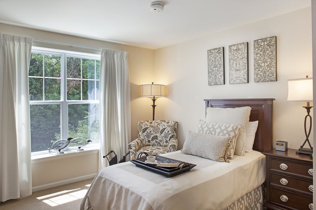 A cozy bedroom with a single bed, large window, and elegant decor.