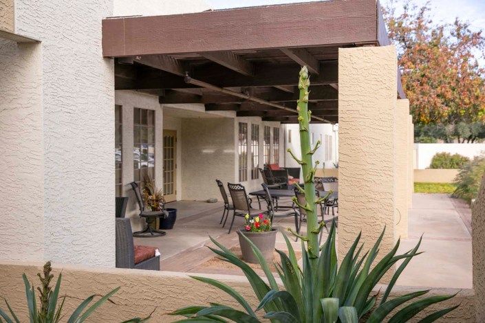A cozy patio area with outdoor seating surrounded by desert landscaping.