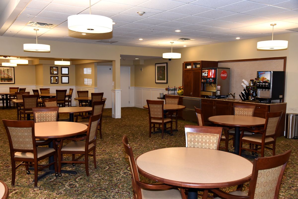 A cozy dining area with round tables and chairs, featuring warm lighting.
