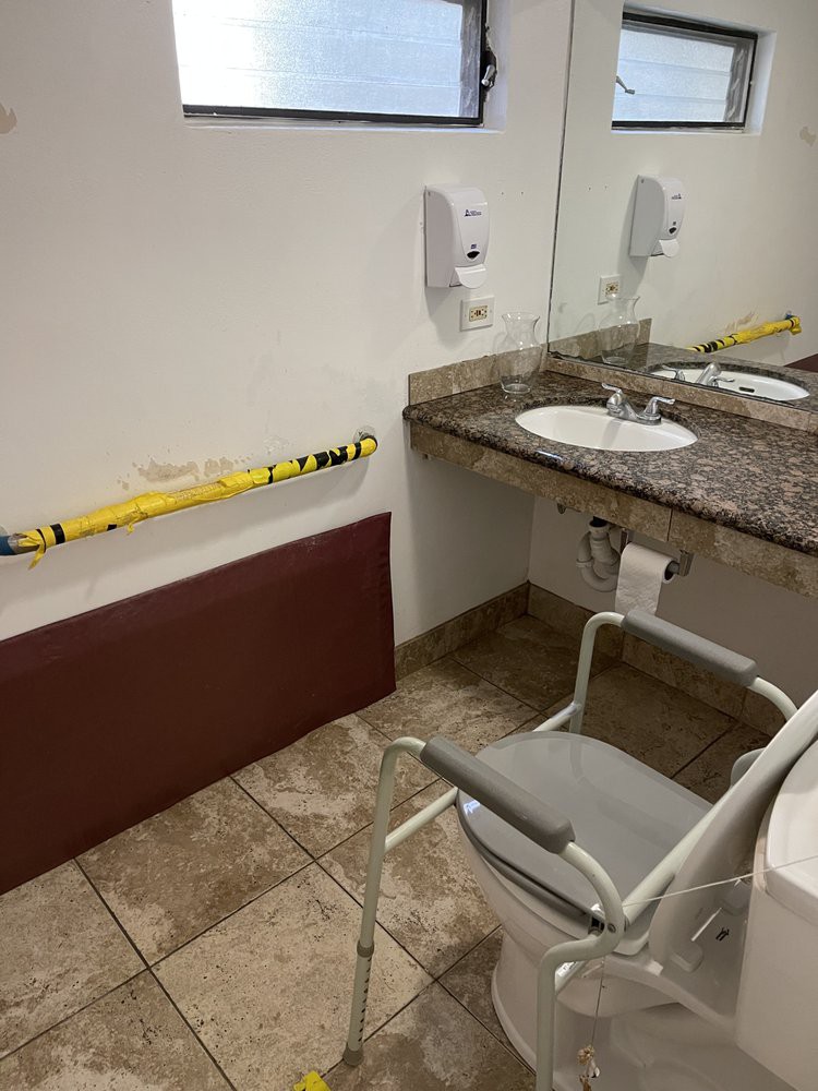 A handicap accessible bathroom with a sink, mirror, and chair.