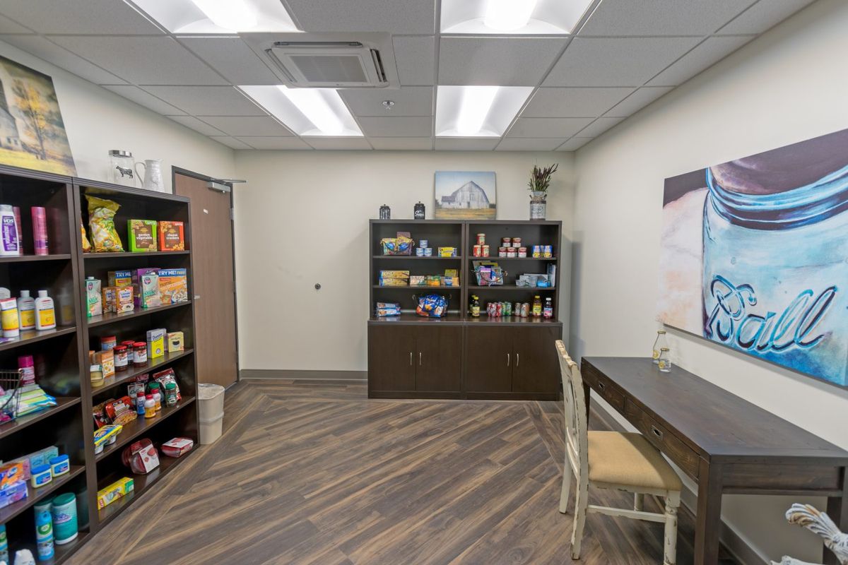 A well-organized office space with shelves of food items and a desk.