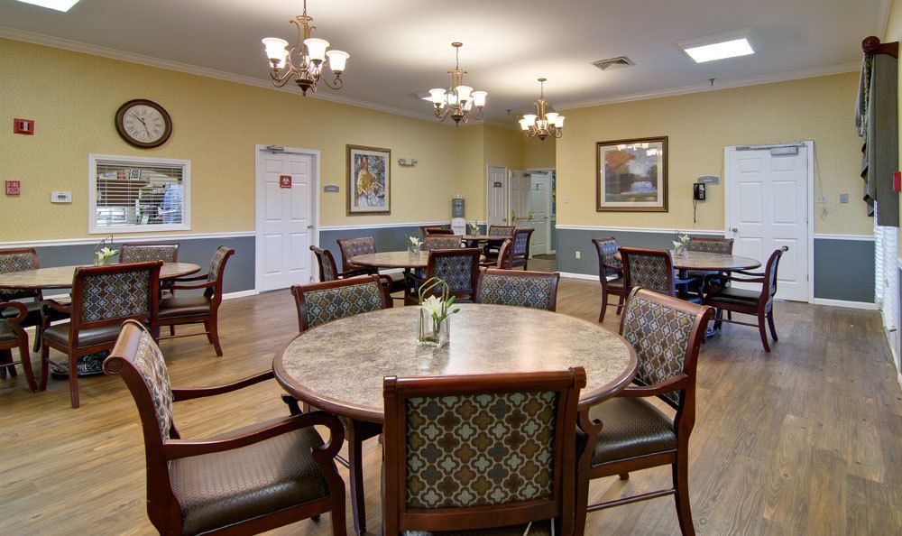 A well-lit dining room with multiple round tables and chairs, featuring elegant decor and warm lighting.