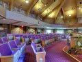 Interior of a church with wooden ceilings and purple pews.