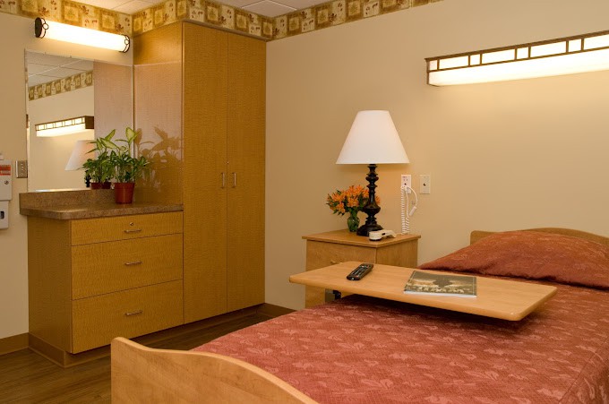A cozy bedroom with a neatly arranged bed, wooden furniture, and soft lighting.