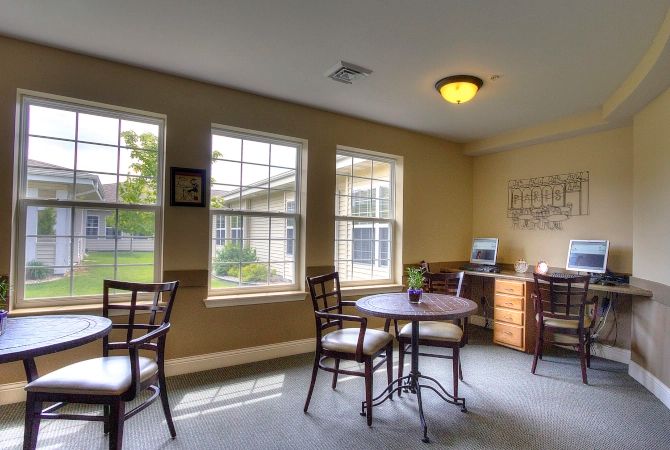 A cozy room with large windows, tables, and chairs.