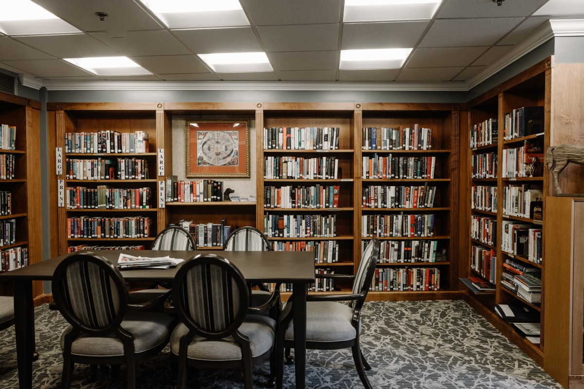 A cozy library reading room with a table and chairs surrounded by bookshelves.
