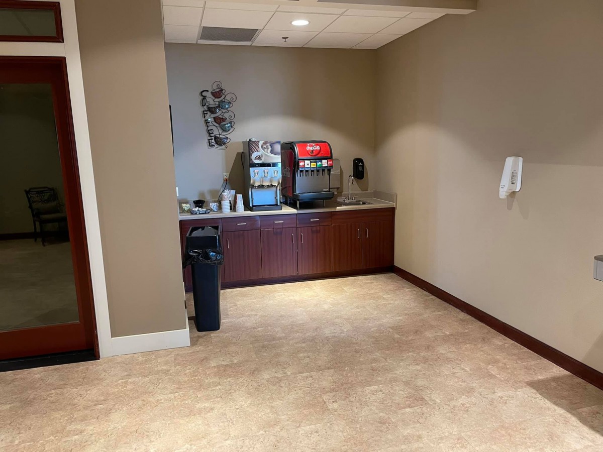 Office beverage station with a coffee machine and sink.