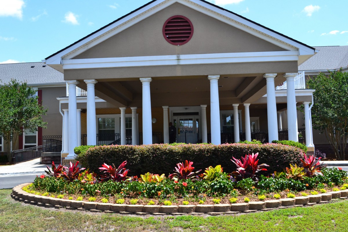 A large building with a columned entrance and landscaped flower beds.