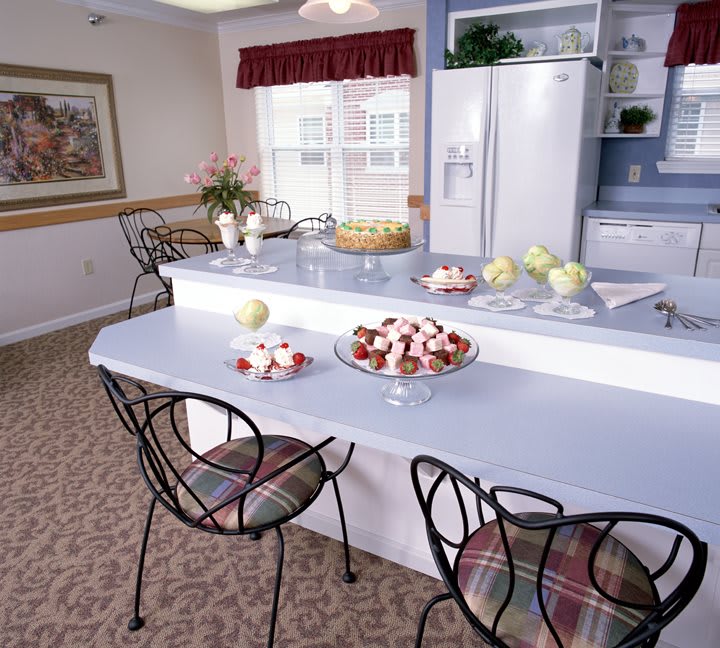 A cozy kitchen with a spacious counter, elegant chairs, and decorative bowls of fruit.