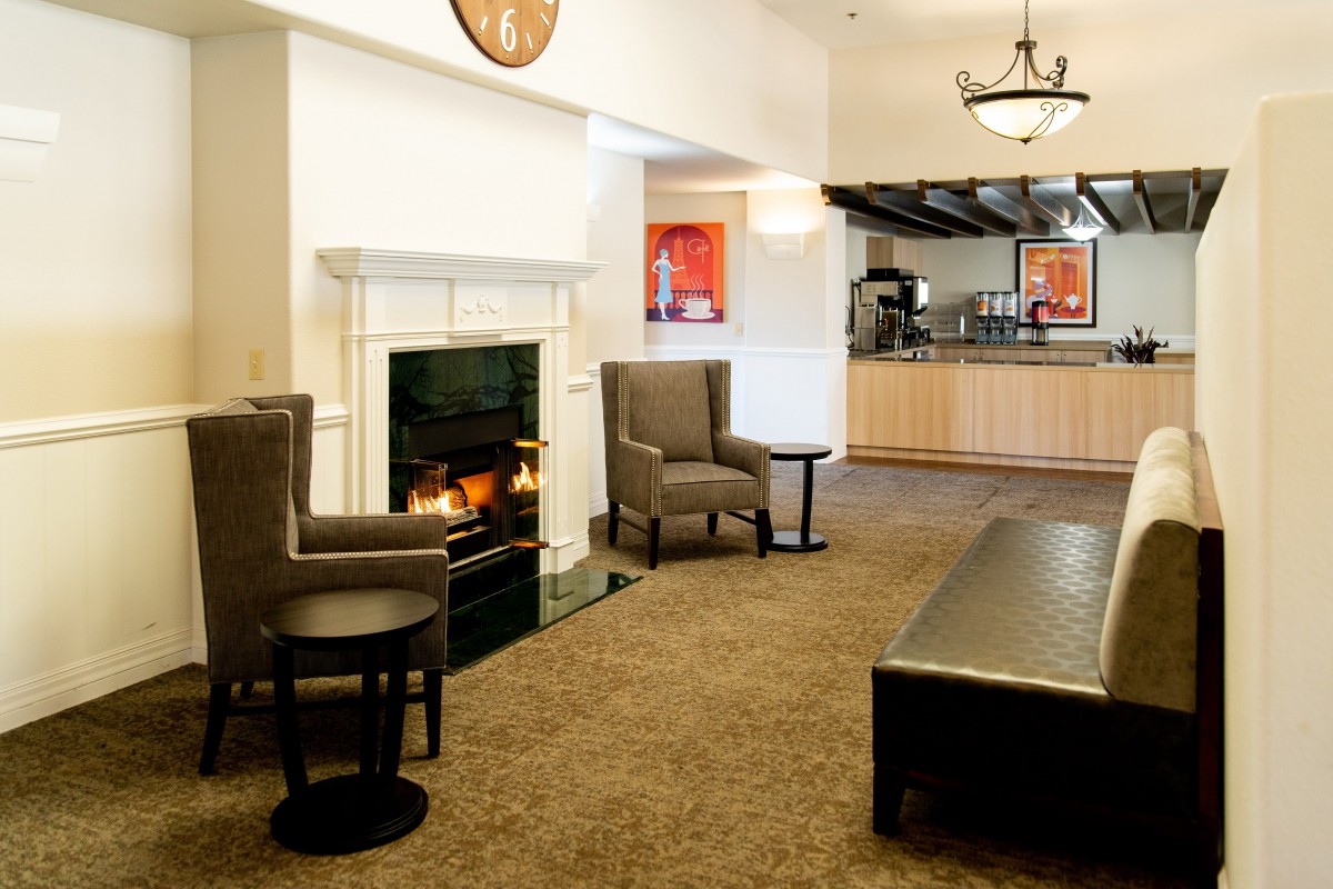 A cozy lobby area featuring a fireplace, armchairs, and a coffee table.