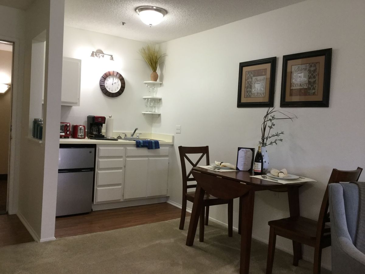 A cozy kitchen and dining area with a small table and chairs, featuring wall art and modern decor.
