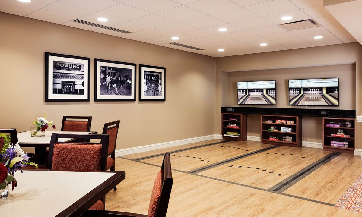 A cozy room with shuffleboard tables, comfortable seating, and framed artwork on the walls.