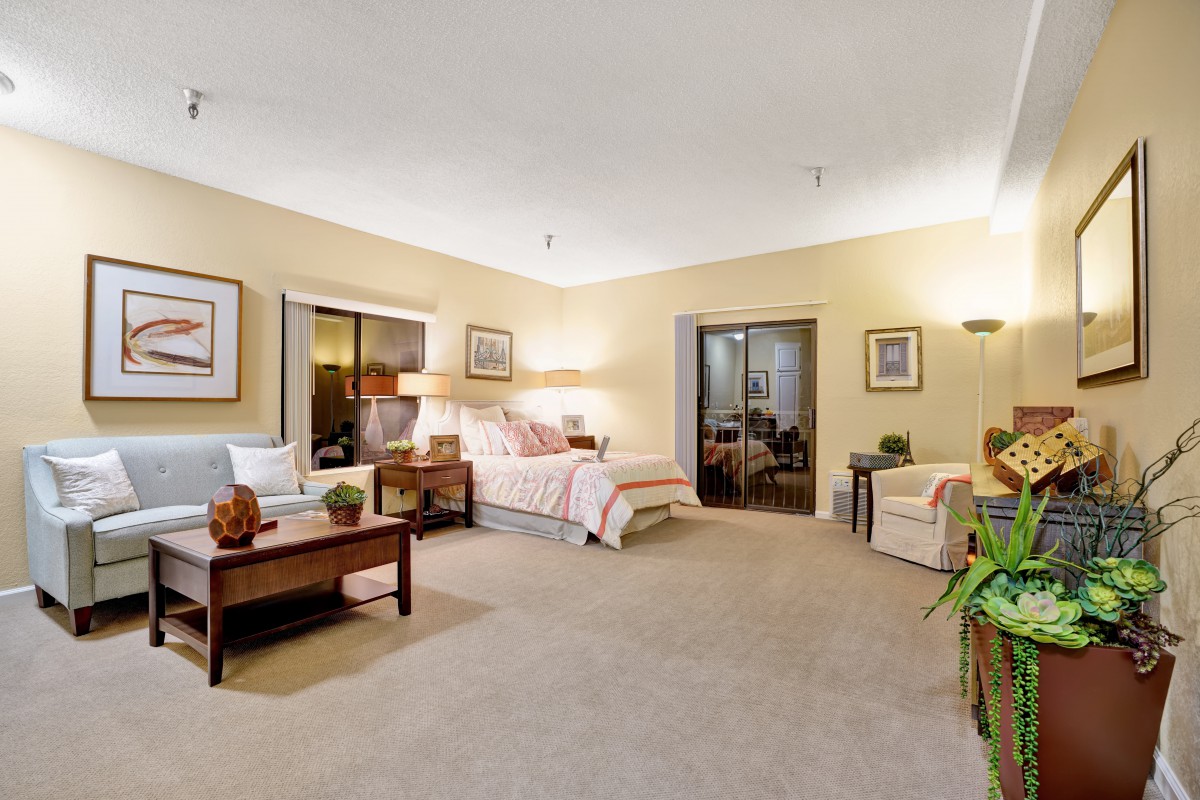 A spacious and cozy bedroom with elegant decor, featuring a comfortable bed, bedside tables, lamps, and a large window letting in natural light.