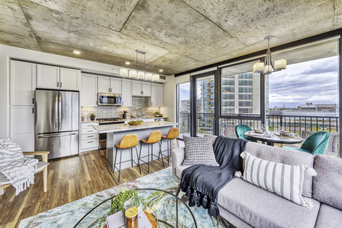 Modern open-concept apartment with a living room and kitchen featuring large windows and stylish decor.