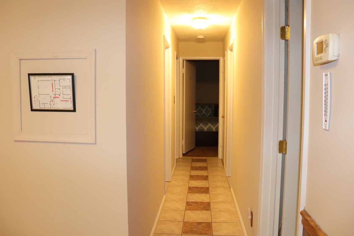 A well-lit hallway with tile flooring and multiple doors.