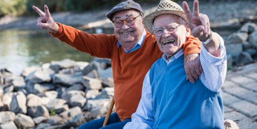 Two elderly men enjoying a sunny day by the water, sharing smiles and friendship.