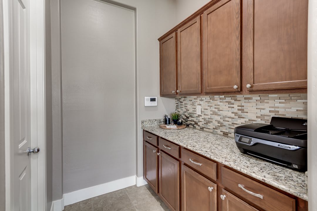 A modern kitchen with wooden cabinets, granite countertops, and a mosaic backsplash.