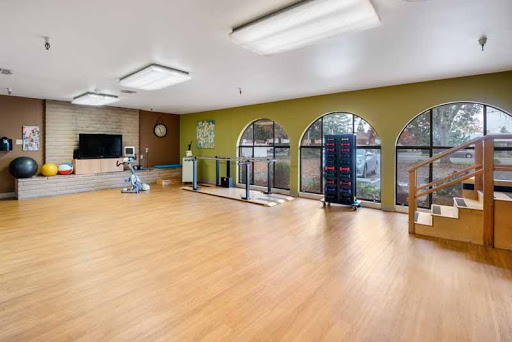 A spacious and well-lit rehabilitation room designed for physical therapy and exercise.