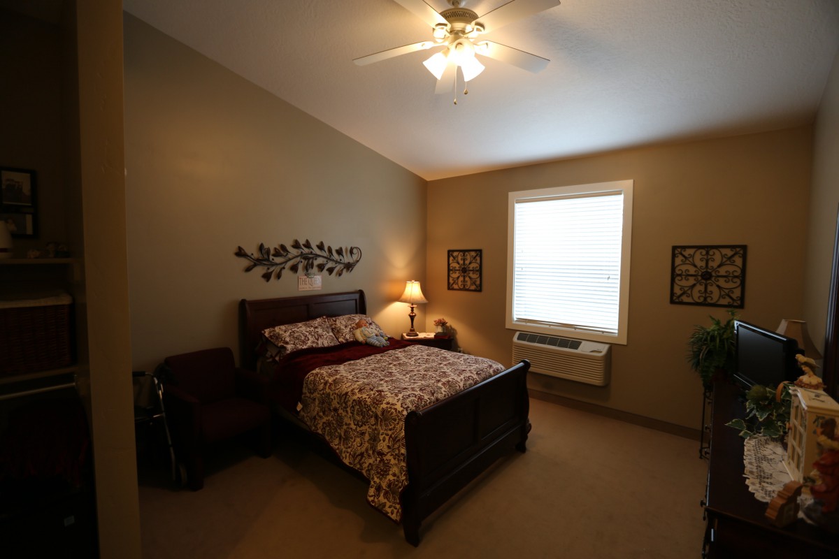 Cozy bedroom with a wooden bed, bedside lamp, and window.