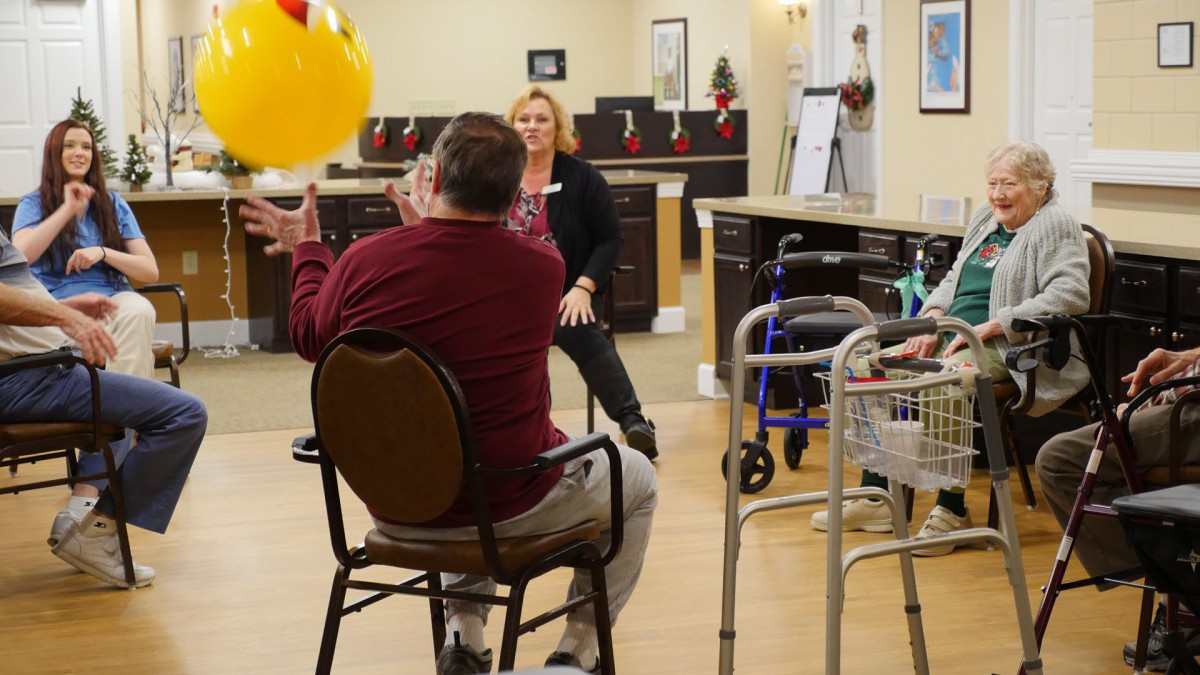 A group of seniors engages in a therapeutic ball exercise indoors, promoting physical activity and rehabilitation.