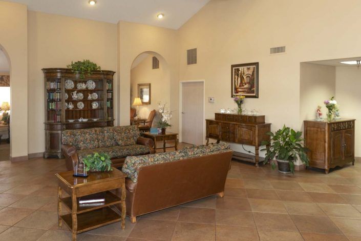 A cozy living room with seating, plants, and decorative furniture.