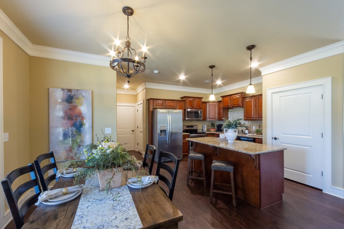A modern kitchen and dining area with wooden cabinets, an island counter, and stylish lighting fixtures.