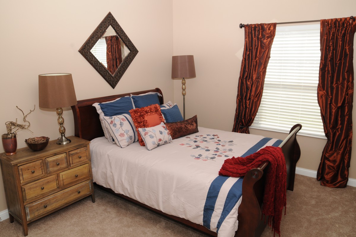 A cozy bedroom with a neatly made bed, decorative pillows, and warm lighting.