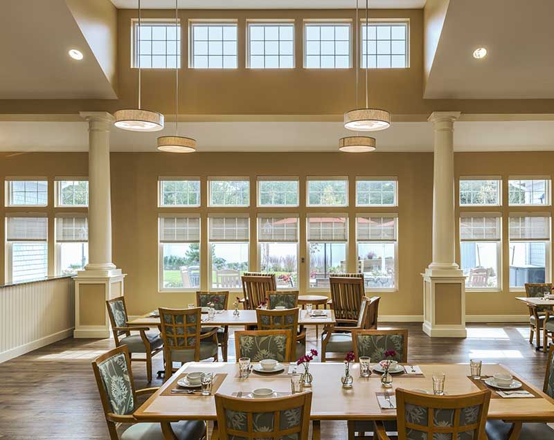 A beautifully lit dining room with large windows and elegant furniture.