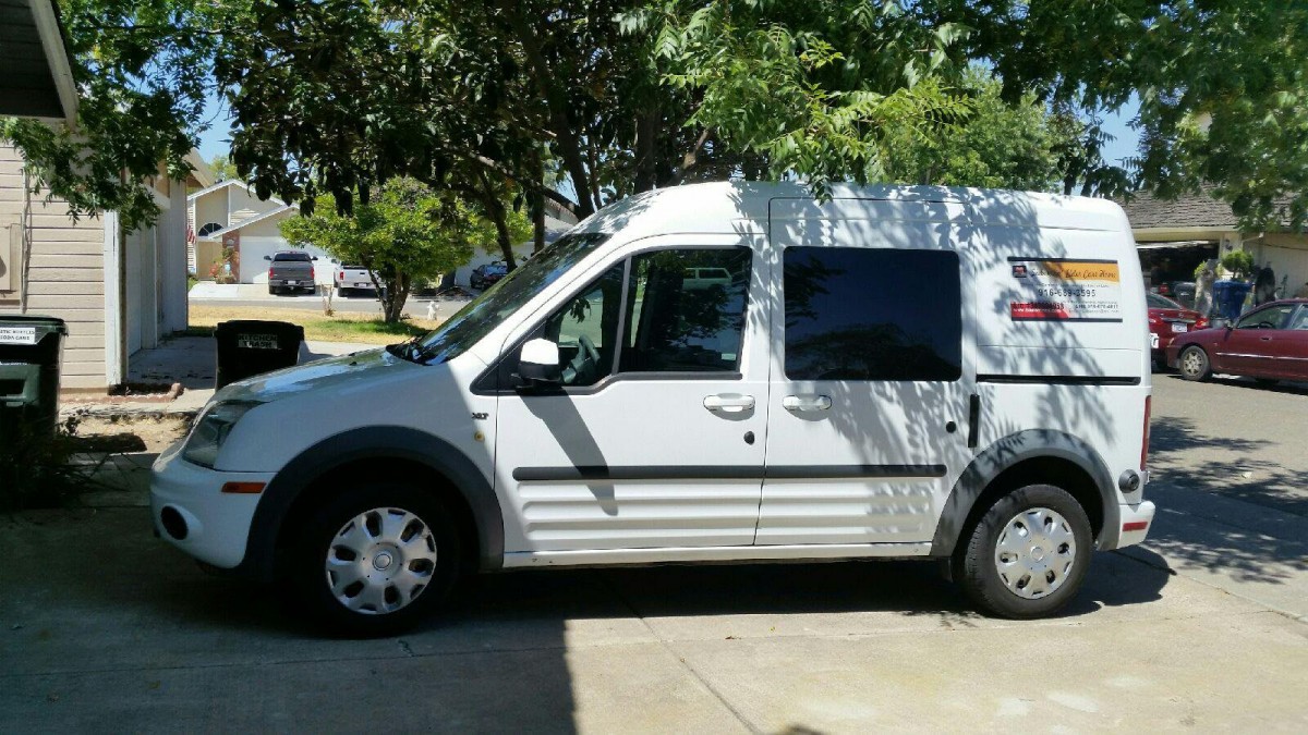 A white van parked in a driveway on a sunny day.