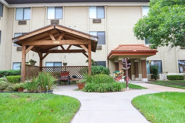 A residential building entrance with a wooden gazebo and landscaped pathway.
