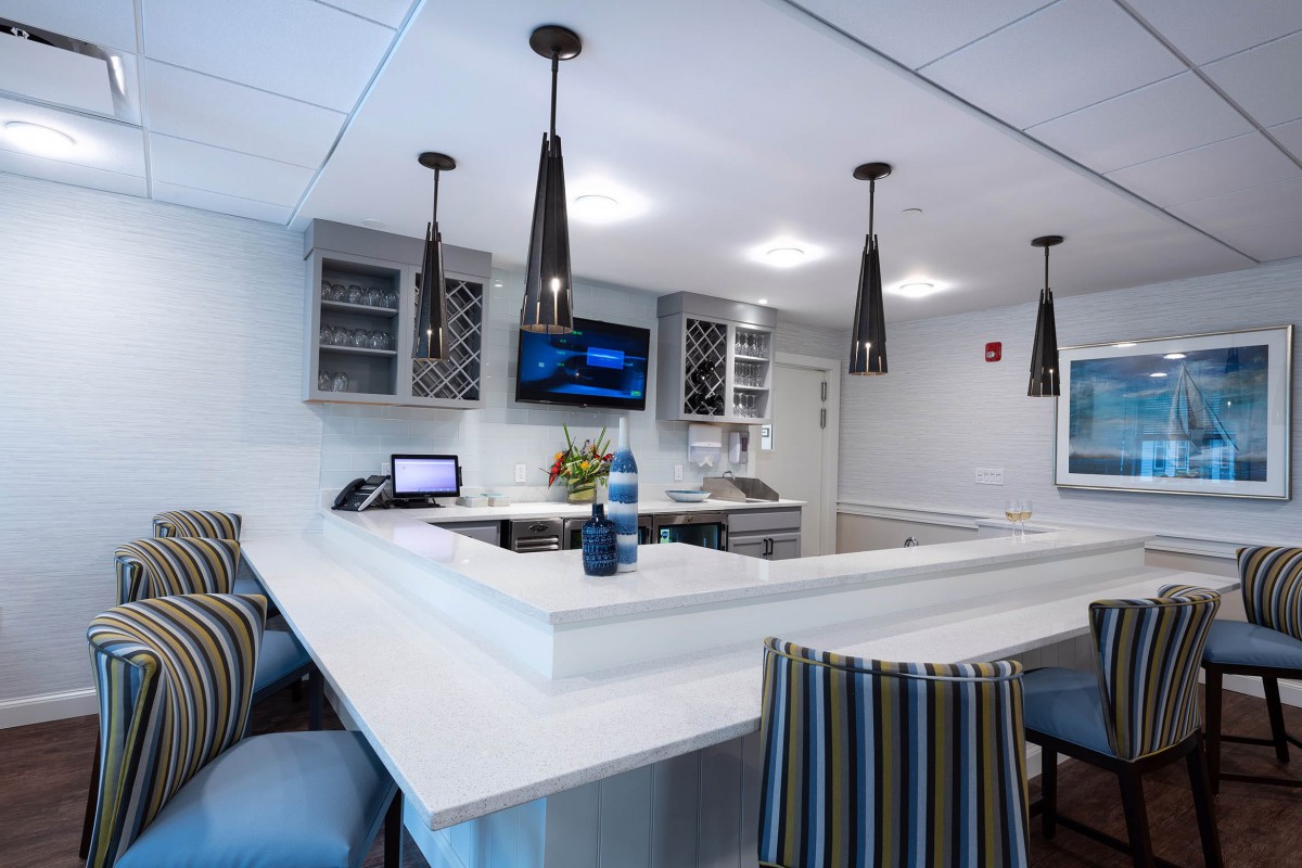 A modern kitchen interior with stylish pendant lighting and striped chairs around a sleek countertop.