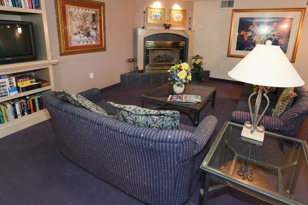 A cozy living room with a striped sofa, coffee table, and a fireplace accented by artwork on the walls.