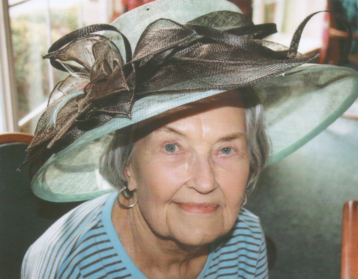 An elderly woman wearing a stylish hat and smiling.