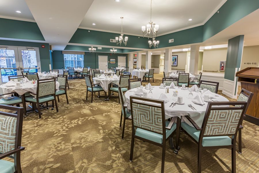 An elegant dining room with neatly arranged tables and chairs, set for a formal gathering.