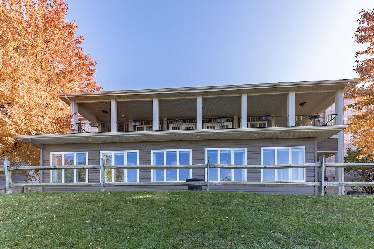 A modern house with large windows and a spacious balcony overlooking a green lawn.