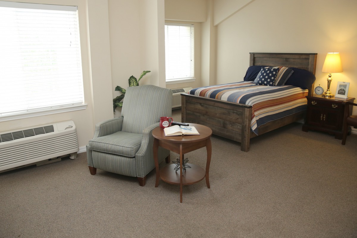 A cozy bedroom with an armchair and a wooden bed.