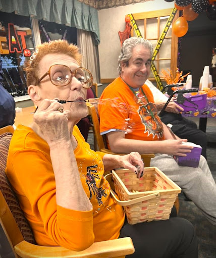 Two individuals enjoying a festive Halloween celebration, wearing orange shirts and participating in fun activities.