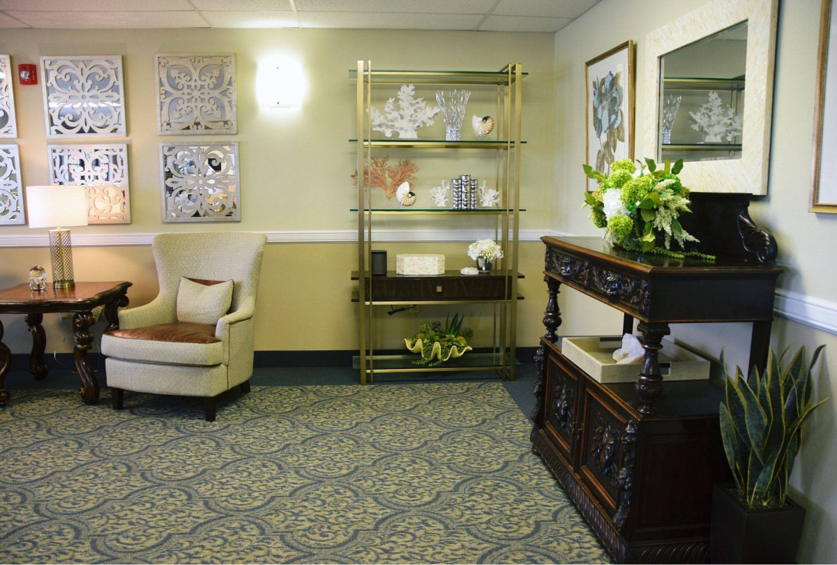 A cozy living room area featuring an armchair, a decorative shelf, and artwork on the walls.