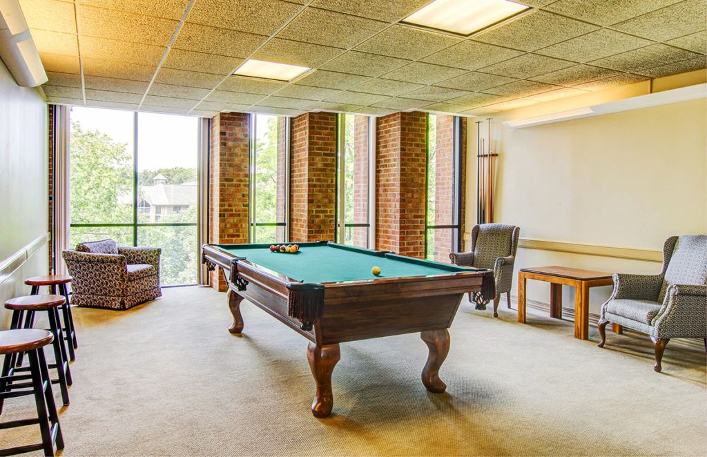 A well-lit game room featuring a pool table and comfortable seating.