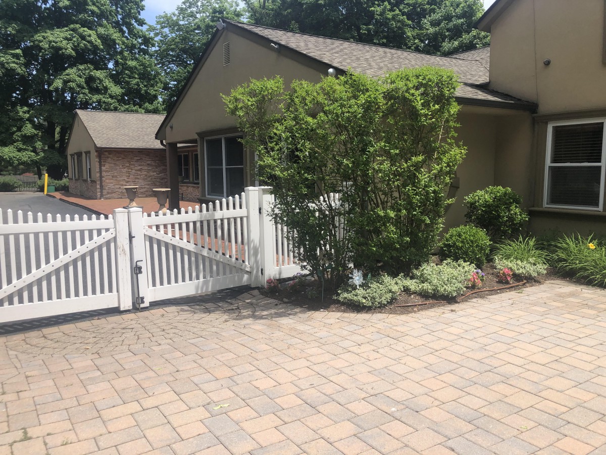 A residential house with a white picket fence and well-maintained landscaping.