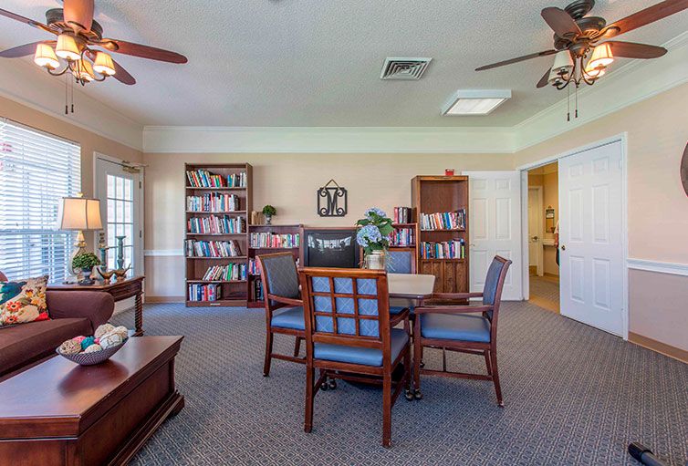 A cozy library room with bookshelves, a table, and chairs.