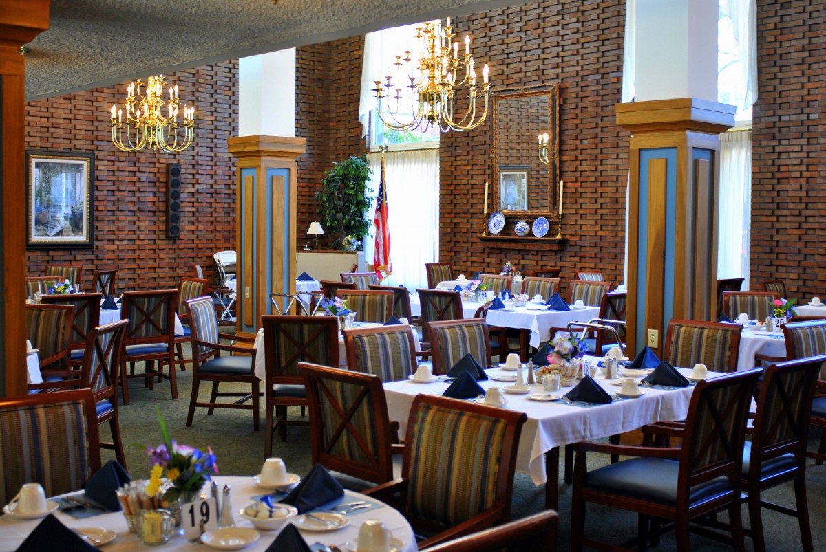 An elegant dining room with beautifully set tables and chandeliers.
