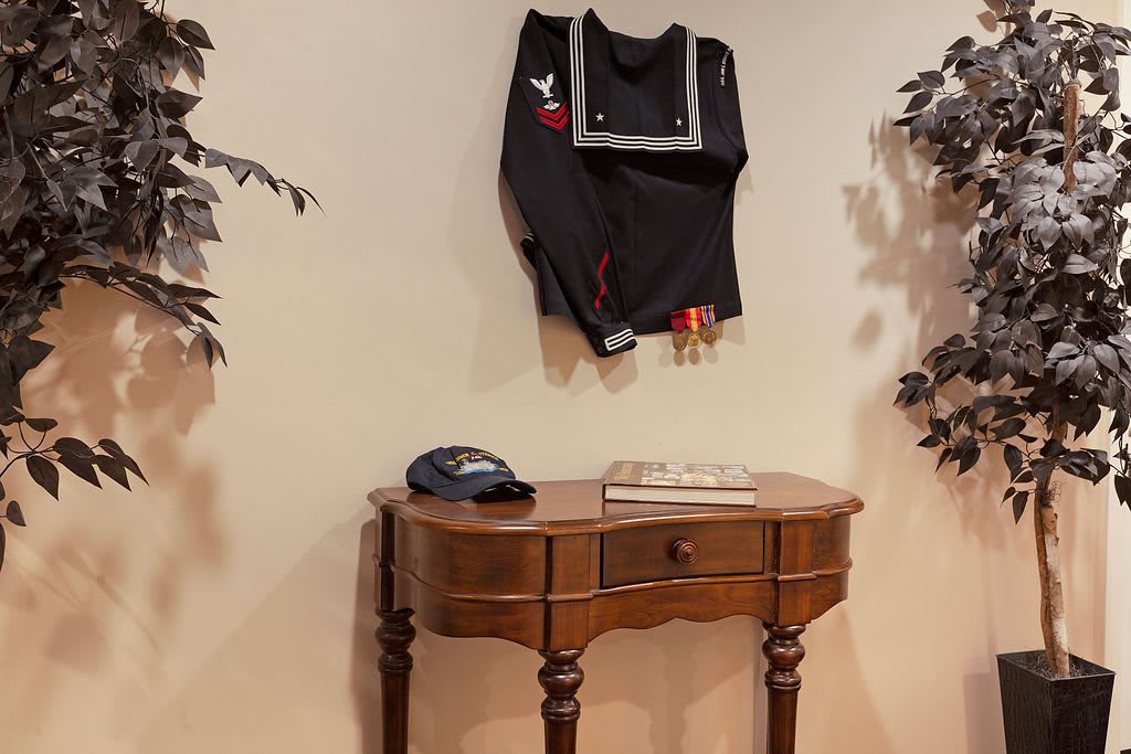 A black jacket hangs on the wall above a wooden table, with a cap placed on the table.