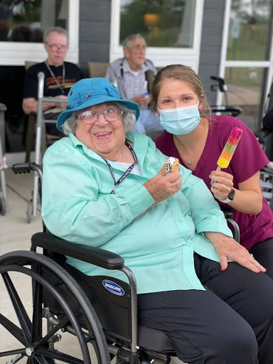 A caregiver and an elderly woman enjoy a cheerful moment outdoors, showcasing the joy of companionship.